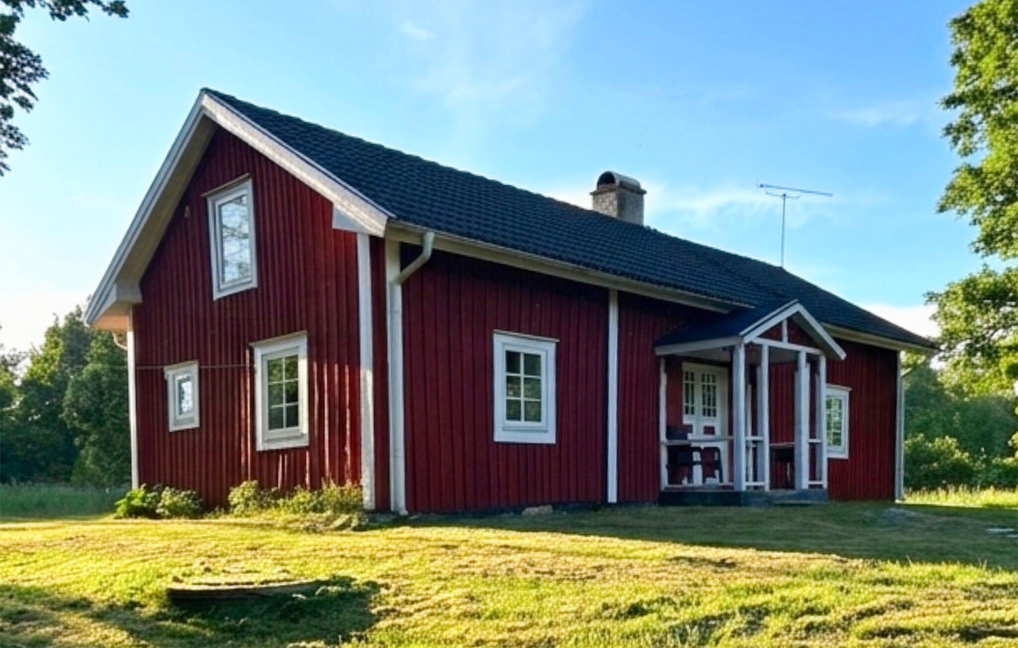 Une maison en bois rouge avec un porche et deux fenêtres.