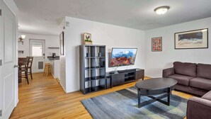 Uma sala de estar com sofá, mesa de centro, TV e estante de livros.