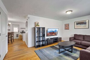A living room with a sofa, a coffee table, a TV, and a bookshelf. - Spacious 3BR Home, Sleeps 6, Near Denver&Red Rocks (Arvada)