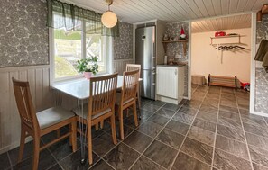 A kitchen with a dining table, chairs, a refrigerator, and a window with a view.