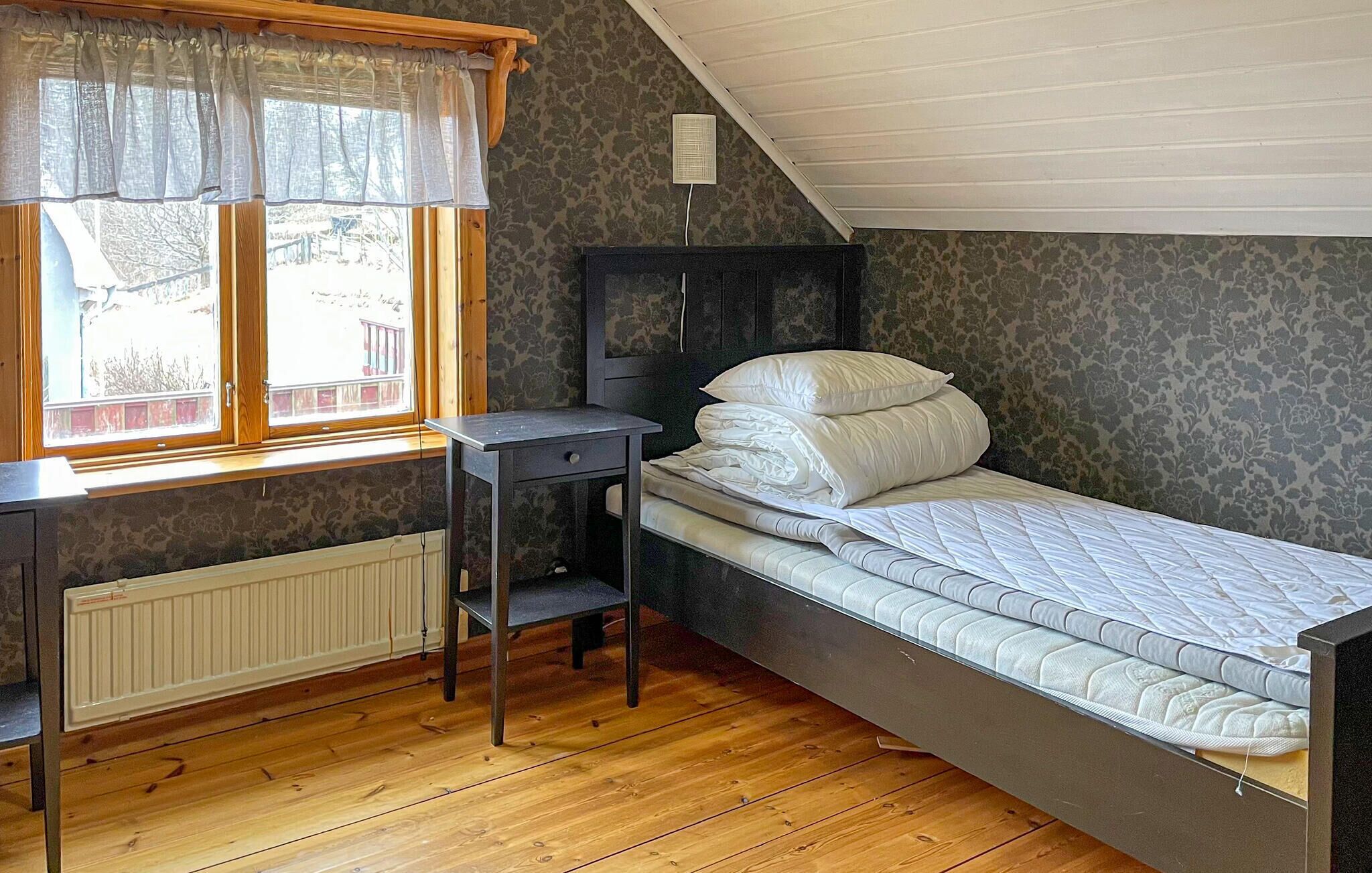 Et lille enkeltværelse med skråvæg, skrivebord og radiator.