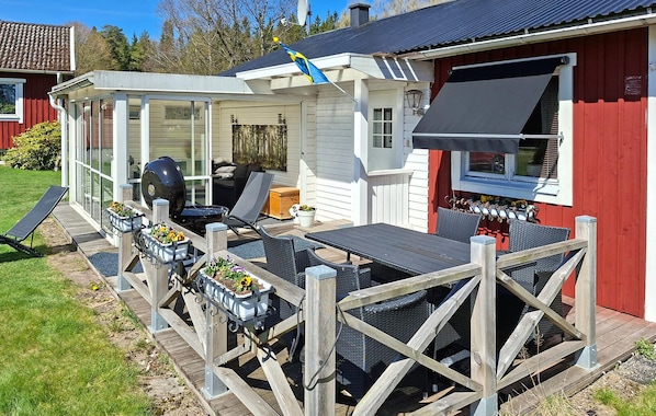 A covered outdoor patio with a grill, seating, and a flag.