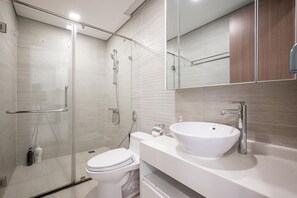 Ein modernes Badezimmer mit einer Duschkabine, einem weißen Waschbecken und einer Toilette.