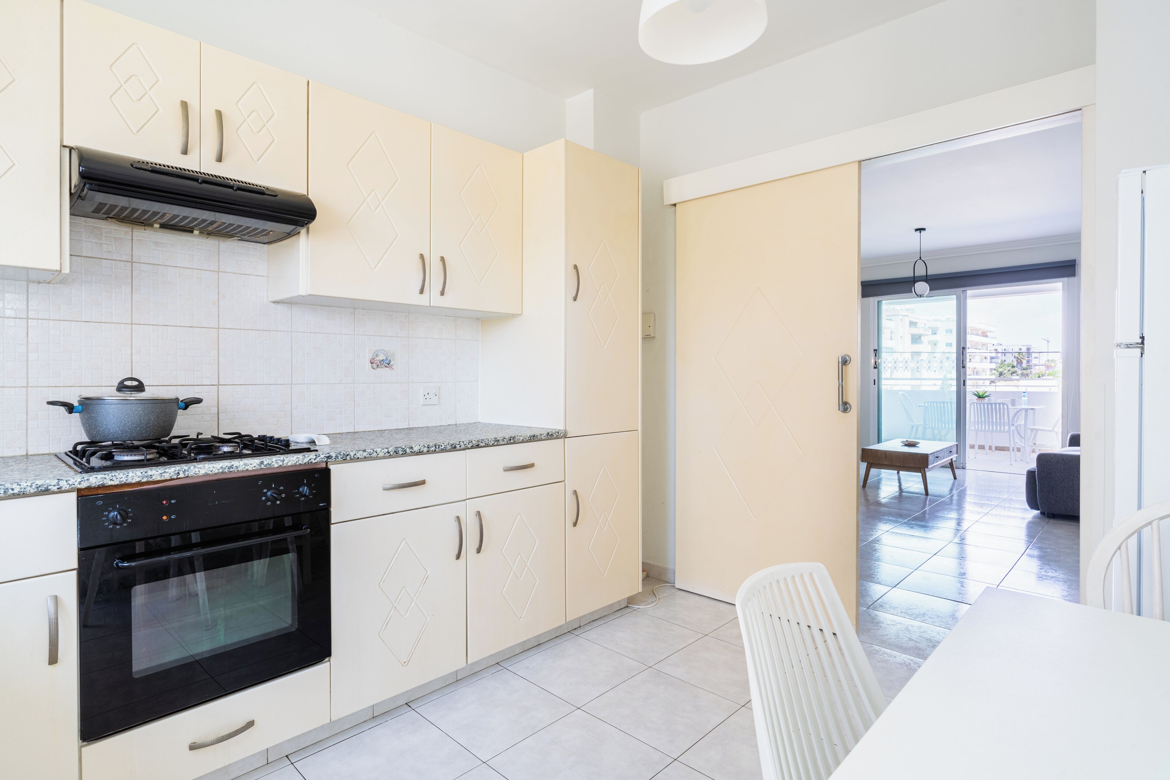 A modern kitchen with a stove, oven, and cabinets. There is a dining area with a table and chairs.