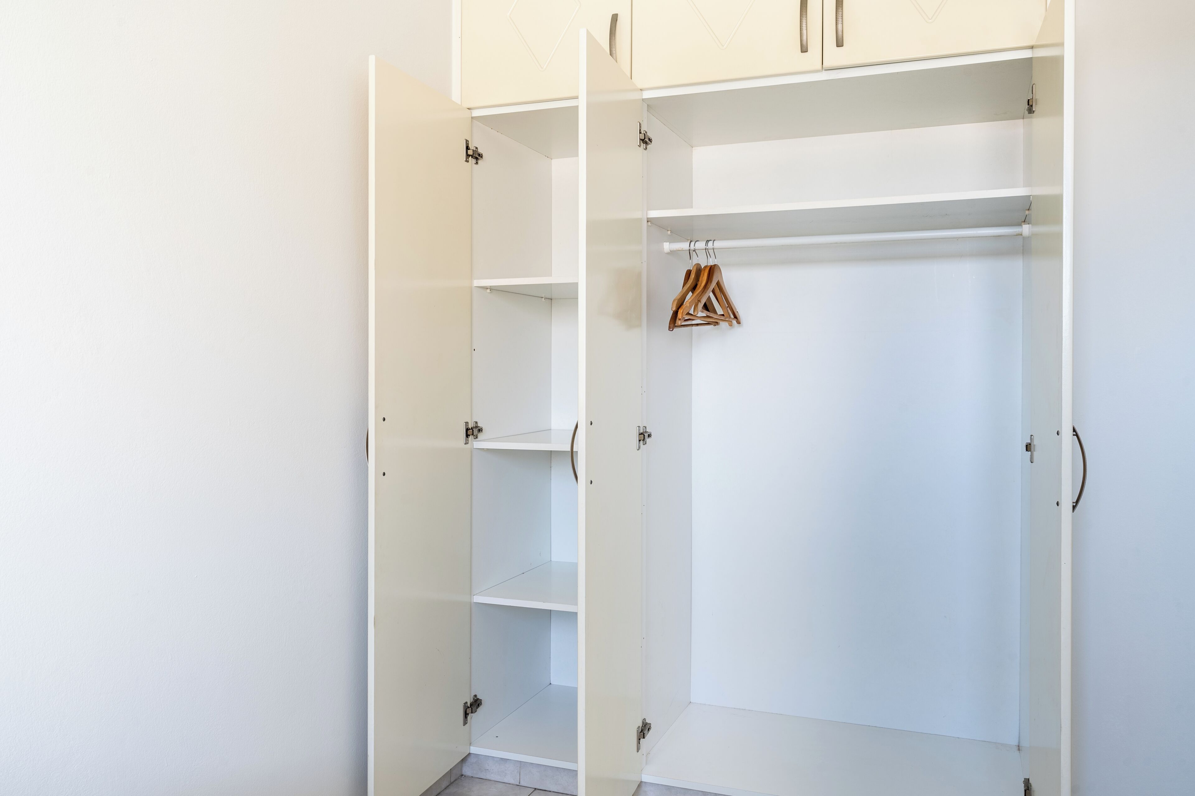 Une armoire blanche dotée de nombreuses étagères et d’un espace pour suspendre les vêtements.