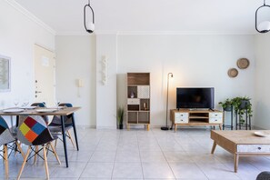 Ein modernes Wohnzimmer mit Essbereich, Fernseher und Couchtisch aus Holz.