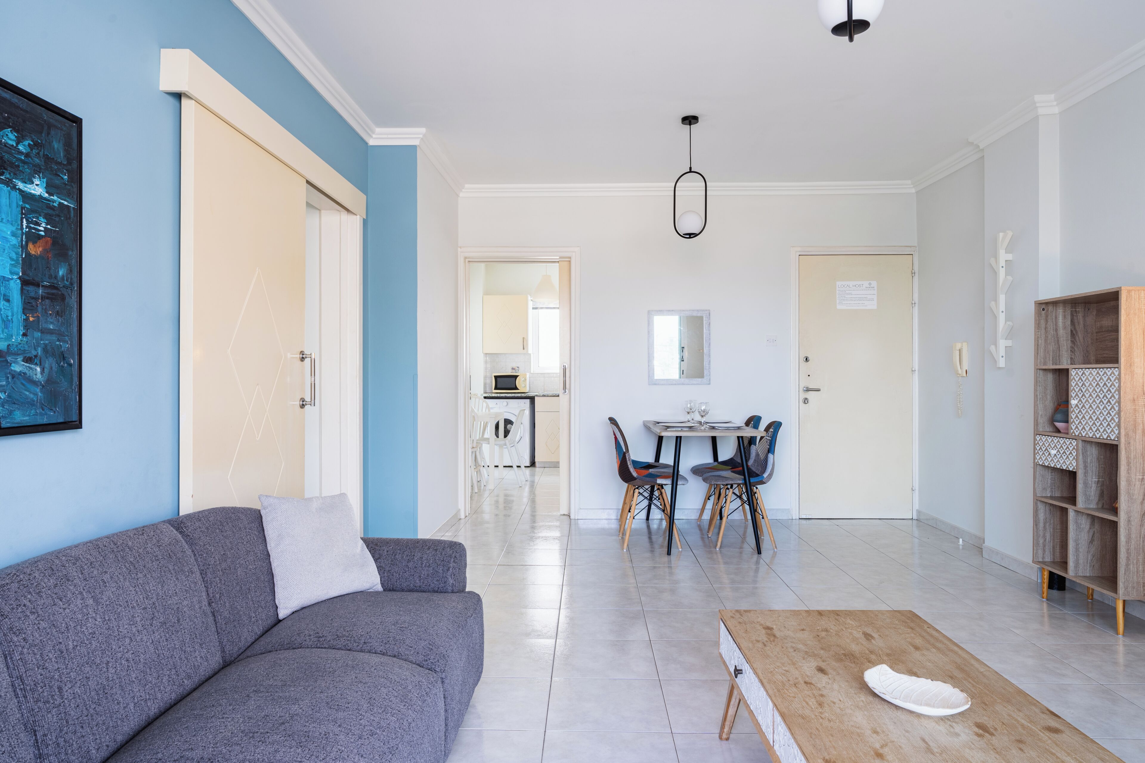 A modern living room with a sofa, a coffee table, and a dining area with chairs and a table.
