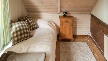 A bedroom with a bed, checkered pillows, a wooden cabinet, and a white rug.
