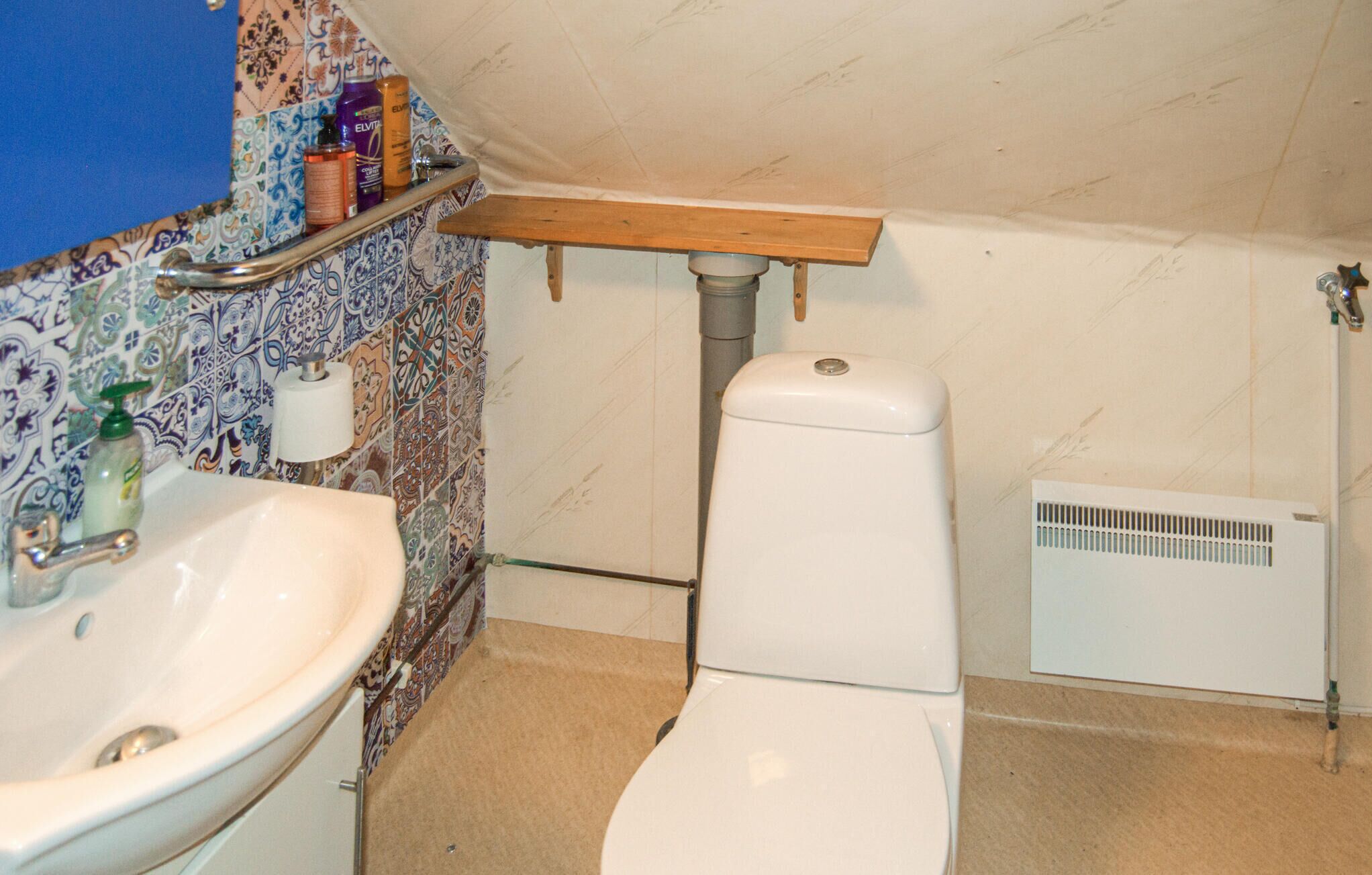 A bathroom with a white sink, toilet, and a shower area.