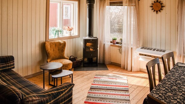 Una habitación acogedora con sofá, una mesita, una silla, chimenea y una computadora portátil sobre una mesa.
