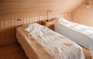 Een kamer met twee bedden, houten wanden, een nachtkastje en een wandlamp.