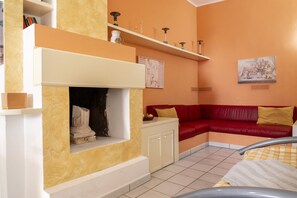 A living room with a fireplace, red sofa, and a tiled floor. - Villa Panoramic | Porto Cesareo beach (Porto Cesareo)