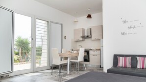 Ein modernes, helles Zimmer mit Essbereich, Küche und einem großen Schiebeglasfenster zum Garten.