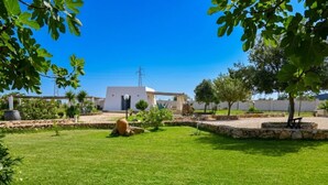 Un edificio blanco con un sendero de piedra, césped y árboles.