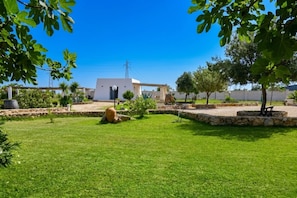 Un bâtiment blanc avec un chemin de pierre, une pelouse et des arbres.