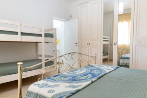 A room with bunk beds, a wardrobe, and a bed with a patterned bedspread. - La Pennichella Apartments - La Pennichella Apartments - Luna (Nardo)