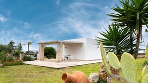 Un edificio moderno e bianco con un patio, posti a sedere all'aperto e piante di cactus.