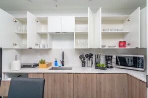 A modern kitchen with white cabinetry, a built-in microwave, and various kitchen utensils. - Miami City Escape 2BR Suite Near Brickell & Miami Beach (Miami)