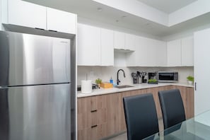 A modern kitchen with stainless steel appliances, wooden cabinets, and a glass dining table.