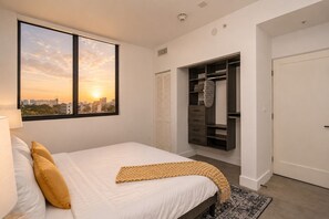 A bedroom with a bed, a window with a city view, a closet with shelves, and a door. - Miami City Escape 2BR Suite Near Brickell & Miami Beach (Miami)