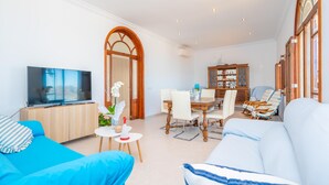 Una sala de estar con televisor, sofá, mesa de comedor y sillas.