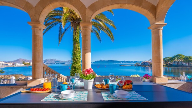 Una mesa dispuesta para el desayuno, con vistas al mar y una palmera.