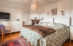 A bedroom with a bed, a television, a dresser, a chair, a fireplace, and a hanging light fixture. - 2 bedroom nice home in Bergsäng (Bergsäng)