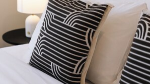 Un letto con biancheria bianca e cuscini a righe bianche e nere.