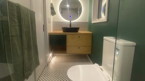 Een badkamer met een toilet, een wastafel met spiegel, vloertegels met een patroon en een groene wand.