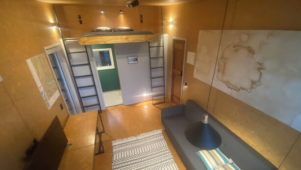 Een moderne kamer met een hoogslaper, een slaapbank, een kamerbreed tapijt met patroon en een kaart aan de muur.