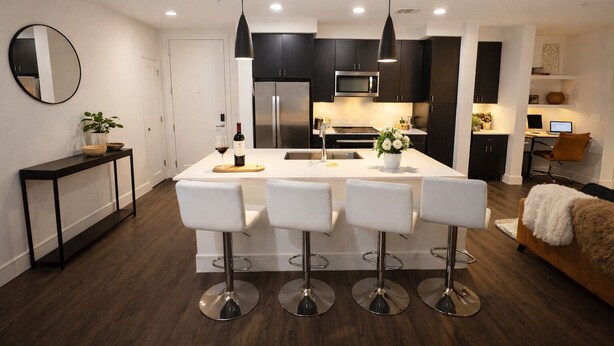A modern kitchen with a central island, bar stools, and pendant lighting. - NRG Jungle Highrise - Balcony & Pool View - Walk to FIFA/NRG/Med Center (Houston)