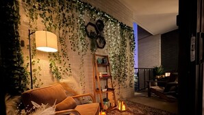 A cozy living room with a brick wall, a wooden chair, a bookshelf, and a patterned rug. - NRG Jungle Highrise - Balcony & Pool View - Walk to FIFA/NRG/Med Center (Houston)