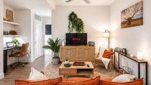 A modern living room with a TV, sofa, and a ceiling fan. - NRG Jungle Highrise - Balcony & Pool View - Walk to FIFA/NRG/Med Center (Houston)
