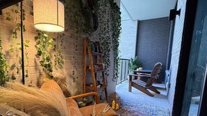 A cozy room with a brick wall, a wooden chair, a small table, and a hanging light fixture. - NRG Jungle Highrise - Balcony & Pool View - Walk to FIFA/NRG/Med Center (Houston)