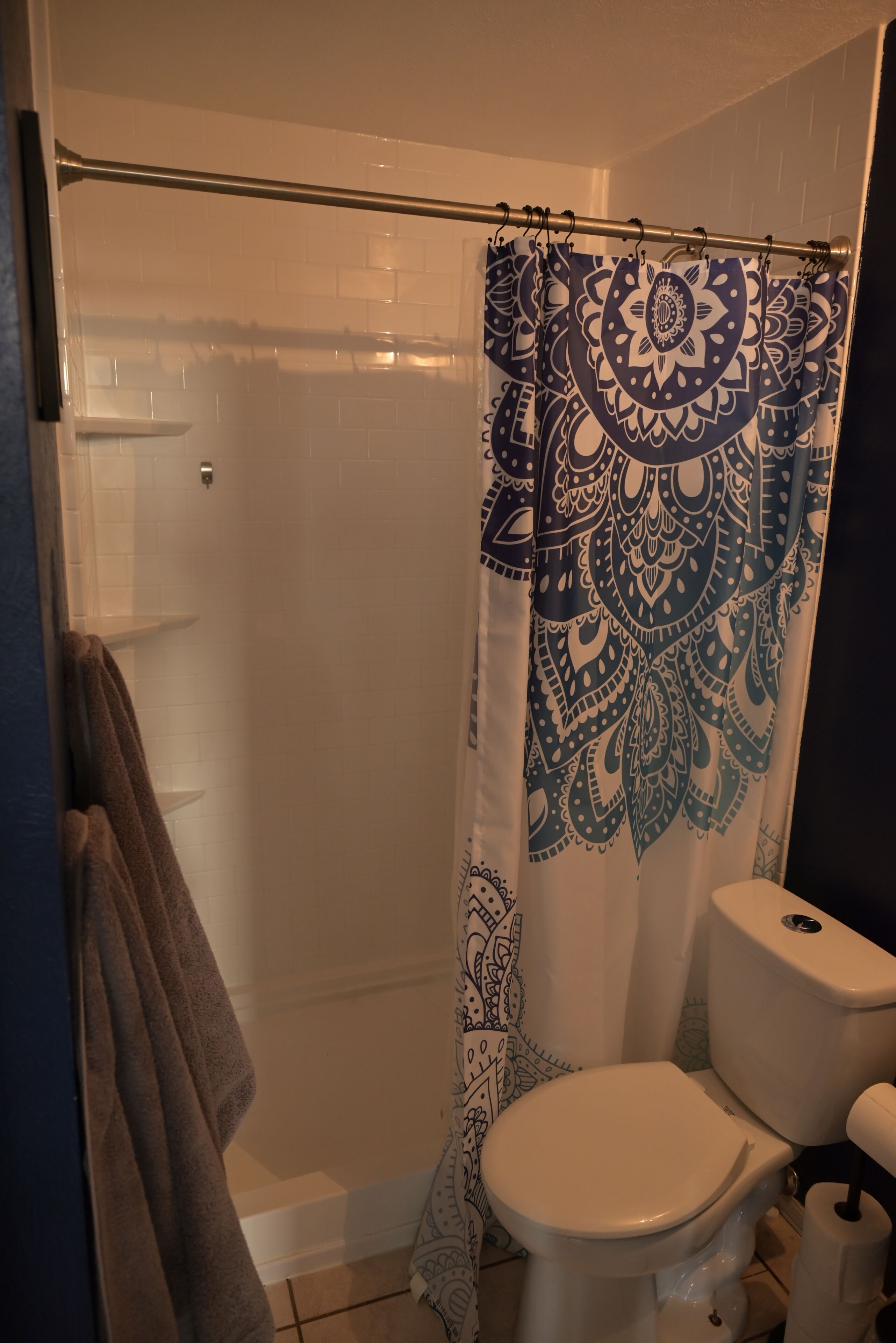 A bathroom with a shower curtain, toilet, and a towel rack.