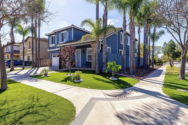 A residential neighborhood with houses, palm trees, and a well-maintained lawn.