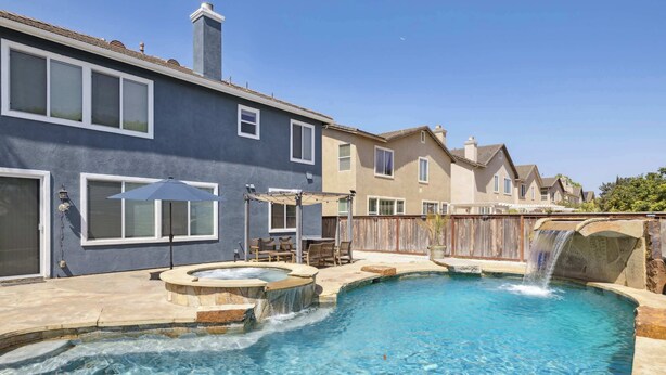 A residential backyard with a swimming pool, a hot tub, and a waterfall feature. - Oxnard Summer Escape with Pool + Hot Tub (Oxnard)