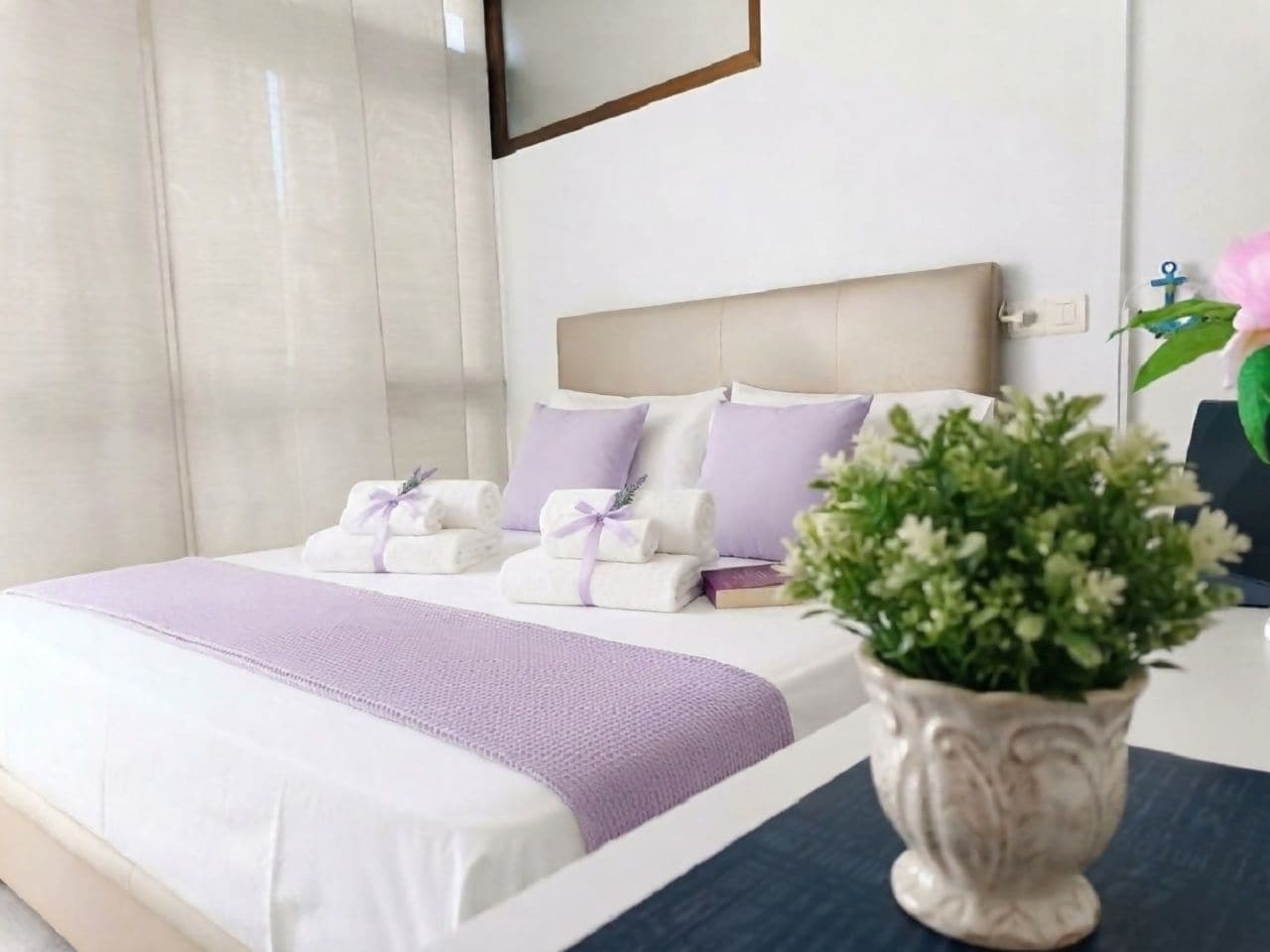 A hotel room with a bed, towels, a potted plant, and a nightstand.