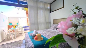 A hotel room with a bed, a dining area, and a view of the outside. - RenTenerife El Romantico (Galletas, Las)