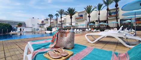 A poolside area with lounge chairs, a towel, and a bag.