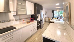 Une cuisine moderne avec des meubles blancs, un plan de travail noir et un coin repas comprenant une table et des chaises.