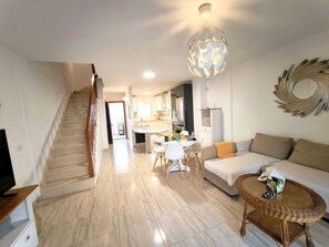 Ein modernes Wohnzimmer mit Treppe, Essbereich und einer Küche im Hintergrund.