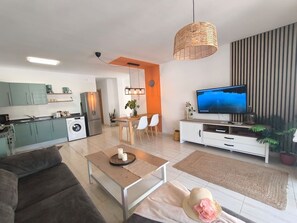 Un salon moderne comprenant un canapé, une table basse, un téléviseur et un coin repas.