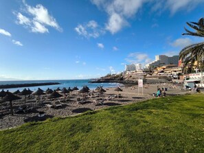 A beach with umbrellas, lounge chairs, and a view of the ocean. - RenTenerife Adeje Sea Views Horizon (Costa Adeje)