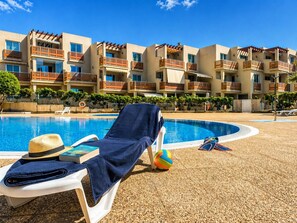 A poolside area with lounge chairs, a hat, and a volleyball. - RenTenerife Elim Ocean (Abrigos, Los)