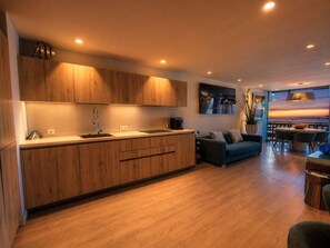 A modern kitchen with wooden cabinets, a built-in sink, and a dining area with a view. - RenTenerife Elim Ocean (Abrigos, Los)