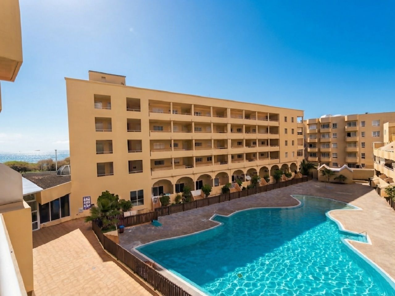 Ein Hotel mit Schwimmbad, mehreren Balkonen und Meerblick.