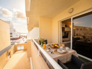 Balkon med spisebord dækket til morgenmad, med udsigt over et boligområde.