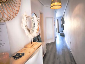 A hallway with a wooden reception desk, a decorative wall piece, and a hanging light fixture. - Rentenerife Casa Lola Medano Beach (Medano, El)