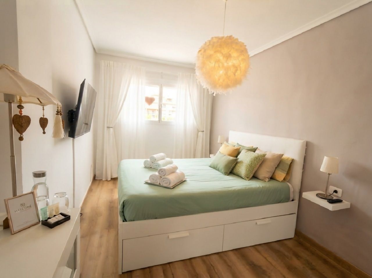 Un dormitorio ordenado con cama, mesita de noche y lámpara colgante.
